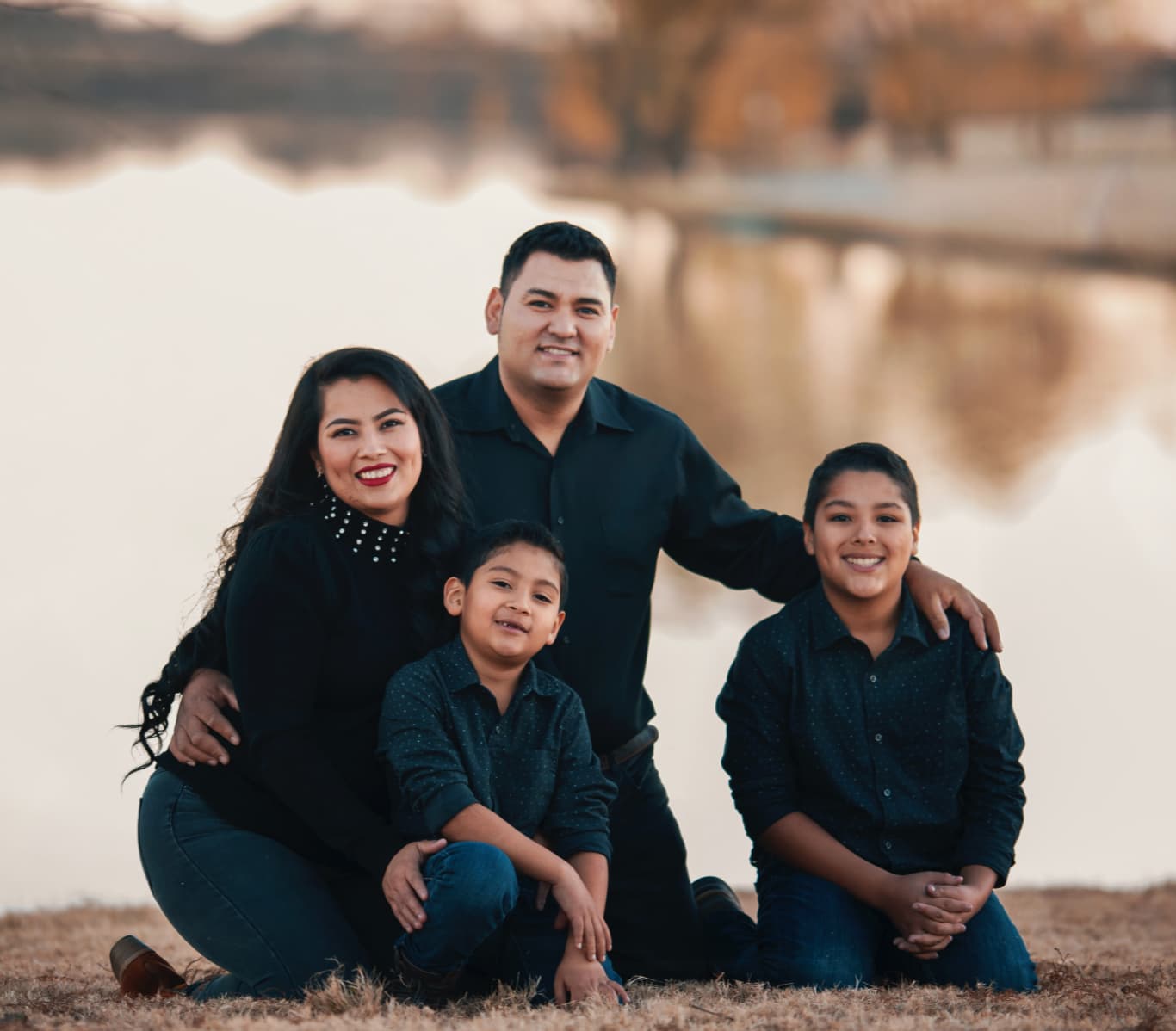 Family of four posing by a lake